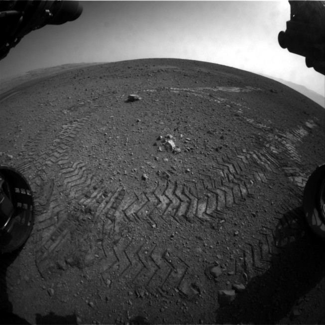 Tracks left on the surface of Mars. This picture was taken using one of the hazard avoidance cameras, which is equipped with a fisheye lens. Photo: NASA/JPL-Caltech.